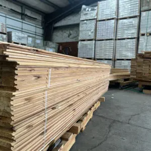 Stacked lumber in warehouse with pallets.