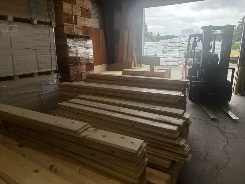 Lumber stacks and forklift in warehouse.