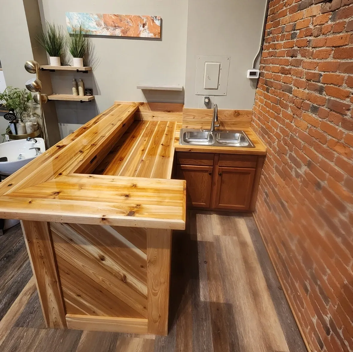 Rustic wooden bar with a brick wall backdrop and plants in the corner.