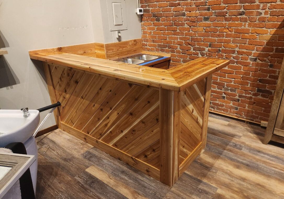 Wooden bar counter with a rustic design and brick wall background.